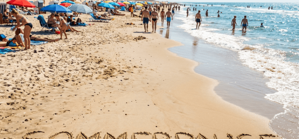 'SOMMERPAUSE' written in sand on a busy beach with sunbathers and swimmers